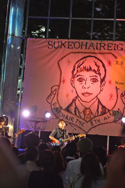 ステージ背景には最新アルバム「8 エイト」のジャケットを巨大化した旗が用意された。