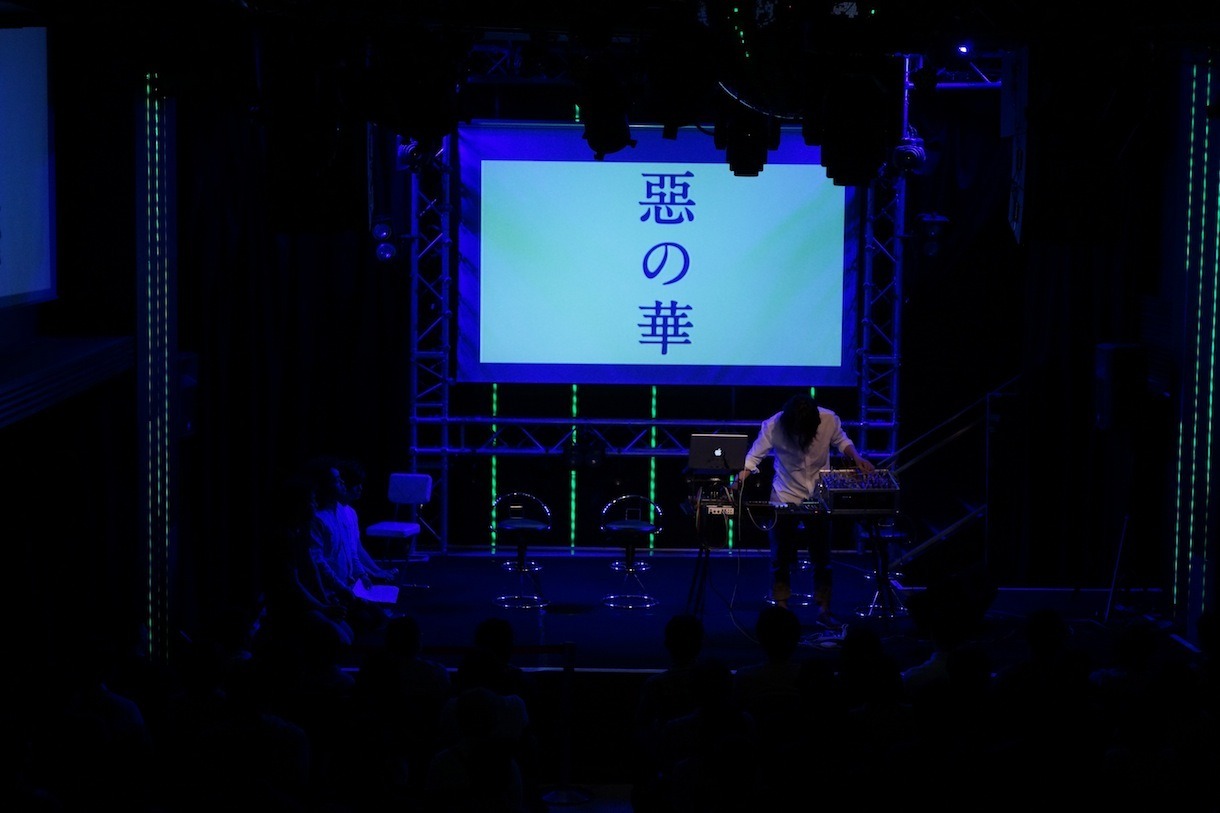 パフォーマンス中の深澤秀行と、正座して聴き入る出演者たち。