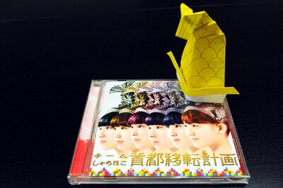 A4サイズの用紙にプリントして作った「“量産型”miniシャチ兜」とチームしゃちほこ「首都移転計画（ジャパニーズ・エディション）」ジャケットのサイズ対比。