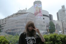 「なんだこれくしょん」のシリンダー広告が掲げられているラフォーレ原宿を背にしたきゃりーぱみゅぱみゅ。