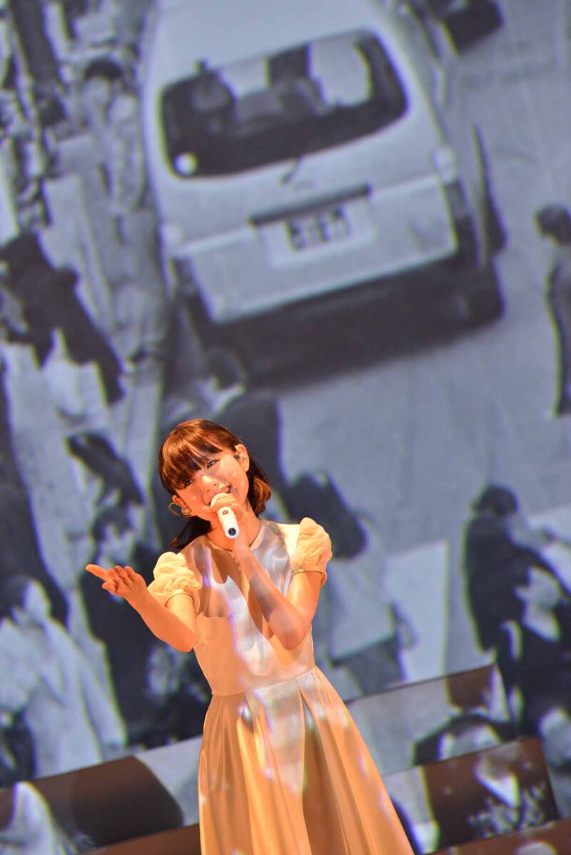渋谷の街を映したムービーをバックに歌う武藤彩未。