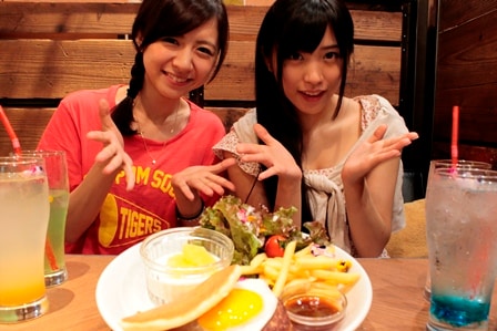 オリジナルメニュー「妄想のロコモコパンケーキ＆PASSPO☆presents 妄想のハワイアンドリンク」を紹介する槙田紗子（左）と根岸愛（右）。