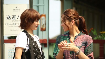 「ミュージャック」のワンシーン。根府川駅前で落ち合う宮澤佐江（SNH48 / 写真左）と秋元才加（AKB48 / 写真右）。