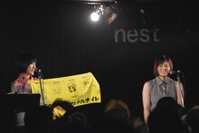 「ナンバタタン・ノ・ズレテルナイト」特製タオルを紹介する野佐怜奈（左）。