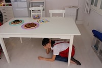 テーブルの下に隠れる秋本帆華。