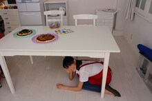 テーブルの下に隠れる秋本帆華。