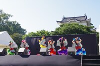 金の鯱がきらめく名古屋城をバックに歌うチームしゃちほこ。