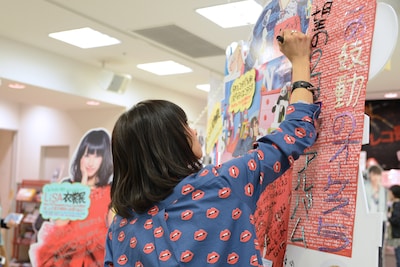 真剣にメッセージを書き入れるLiSA。