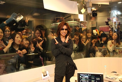 ファンをバックにXポーズを決めるYOSHIKI。