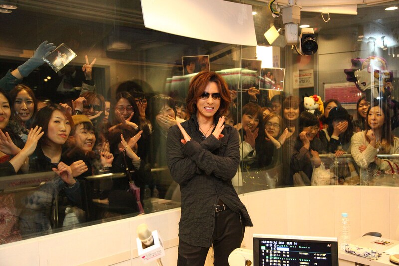 ファンをバックにXポーズを決めるYOSHIKI。