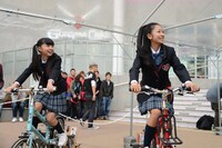 発電用自転車をこぐ内山あみ（左）と藤本杏（右）。