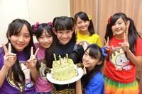 バックヤードでメンバー特製ケーキを持つ根岸可蓮とそれを囲むメンバー。