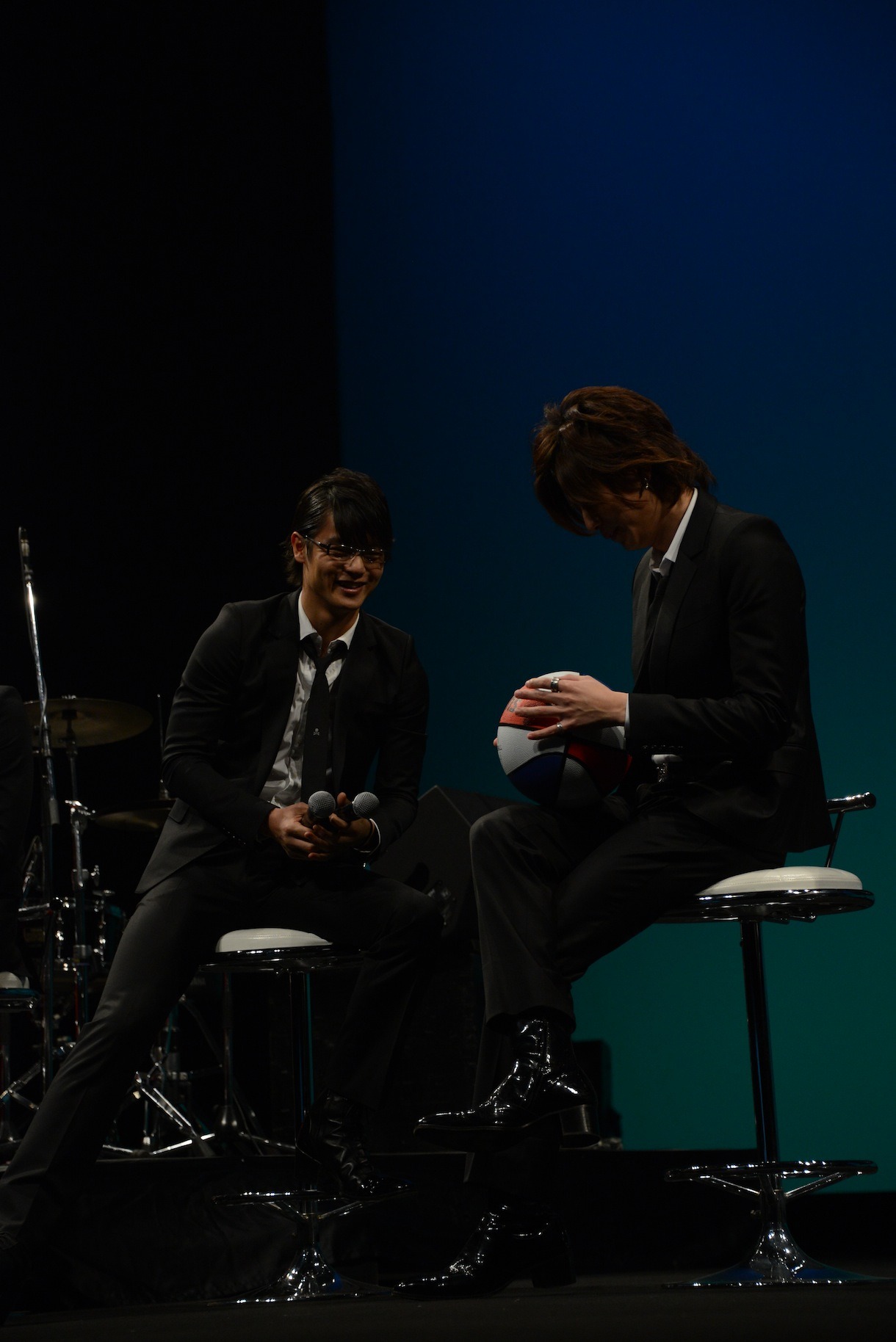 左からバスケットボールにサインを入れる三浦翔平とそれを見守る窪田正孝。