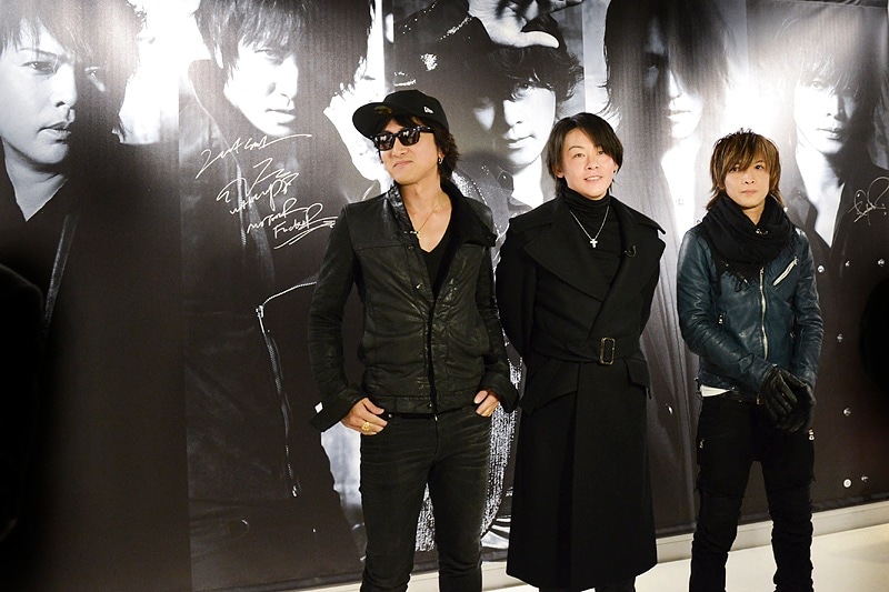 自分たちの特大写真の前に立つJ、RYUICHI、INORAN。