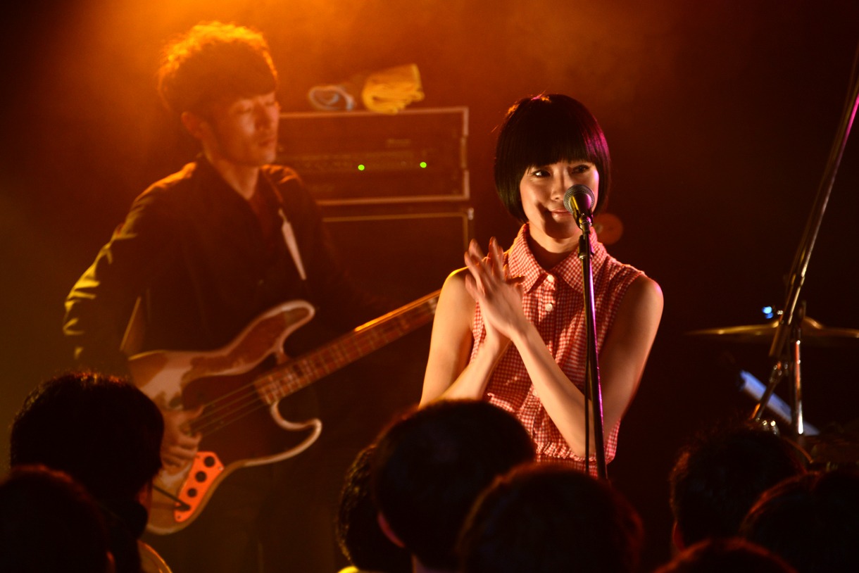 野佐怜奈。後ろでベースを弾いているのはSCOOBIE DOのナガイケジョー。