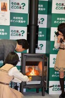 薪ストーブに火を入れる林芳正農林水産大臣と生駒里奈。