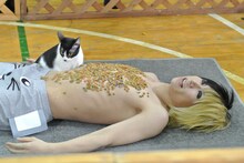 上半身にキャットフードを付け、横たわって猫を待つ歌広場淳（Be-su）。