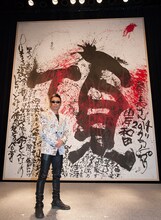 詩画「てっぺん」の前に立つ長渕剛。