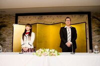 金屏風の前に立つほっちゃん（左）と謎の中年男性（右）。