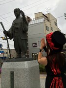 水戸黄門像にライブの成功を祈る吉川友。