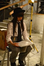 脚立に座って台本をチェックする新井ひとみ。