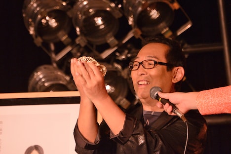 包みを開け本物の小判を取り出したさだまさし。