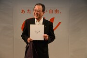 KDDI株式会社 田中孝司代表取締役社長。手に持っているのはティム・クックのサイン入り色紙。