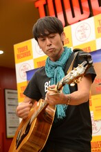 アコースティックギターを爪弾く寺岡呼人。