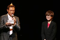 武器屋桃太郎（右）への手紙を読み上げるプロデューサー・はなわ（左）。