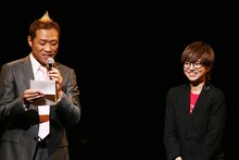 武器屋桃太郎（右）への手紙を読み上げるプロデューサー・はなわ（左）。