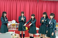 低周波マッサージ機を手に付けた秋元真夏（中央）。