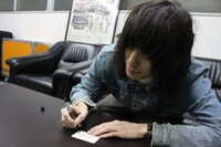 「the dresscodes "1" ENTRY CARD」にサインを書く志磨遼平。