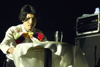 テーブルクロス引きに挑戦する安西卓丸（B, Vo）。（撮影：中島未来）