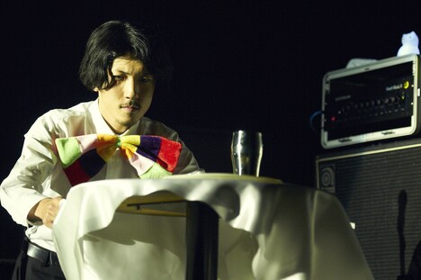 テーブルクロス引きに挑戦する安西卓丸（B, Vo）。（撮影：中島未来）