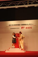 子供の年賀状投函をサポートする桜井玲香（右）。