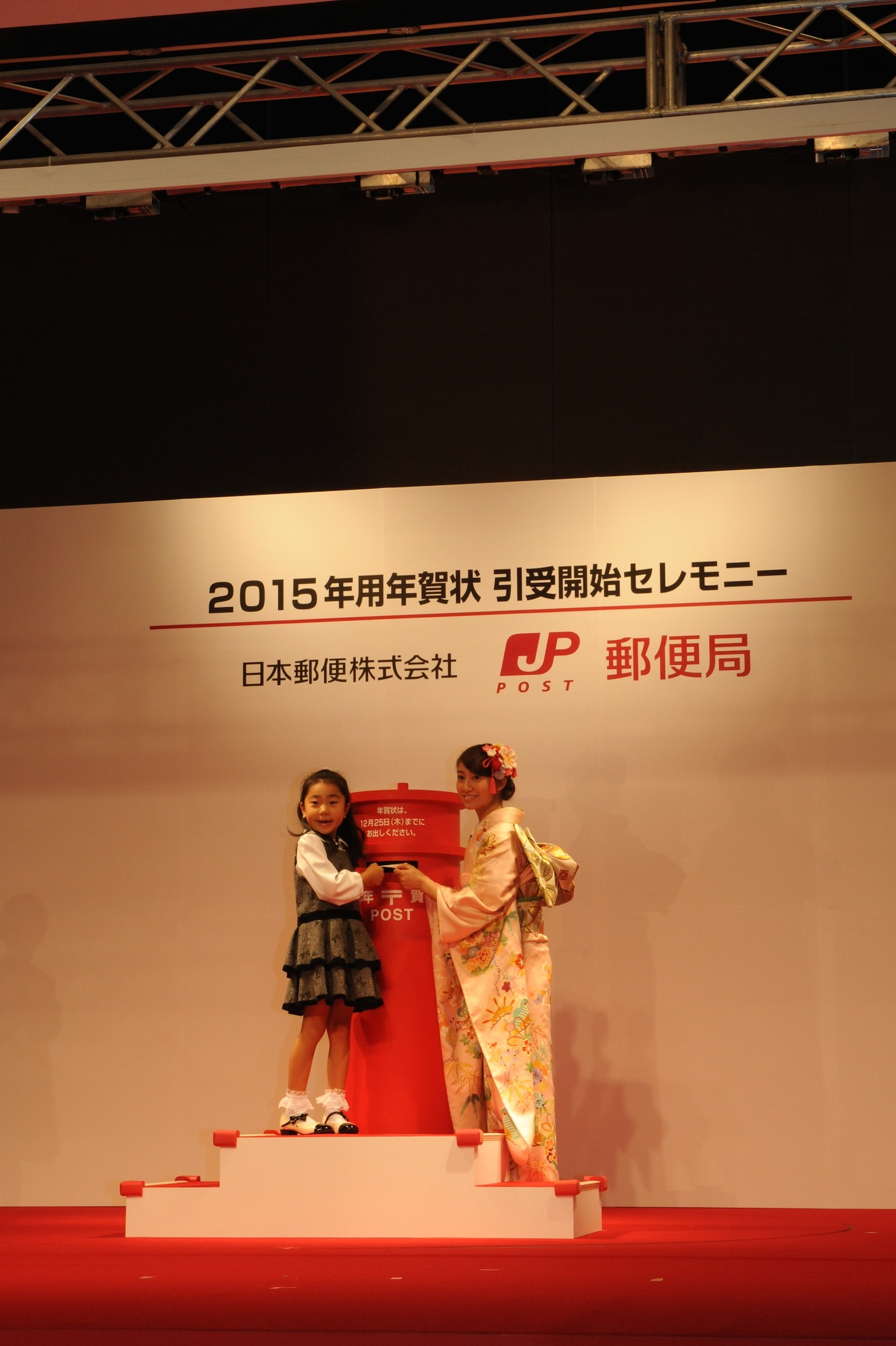 子供の年賀状投函をサポートする桜井玲香（右）。