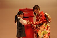 子供の年賀状投函をサポートする白石麻衣（右）。