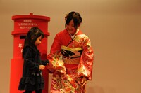 子供の年賀状投函をサポートする星野みなみ（右）。