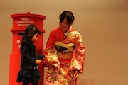 子供の年賀状投函をサポートする星野みなみ(右)。