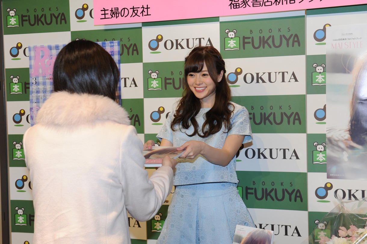 ファンにフォトブックを手渡す白石麻衣（乃木坂46）。