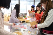 つまみ食いしながら雷おこしを袋詰めする乙女新党。