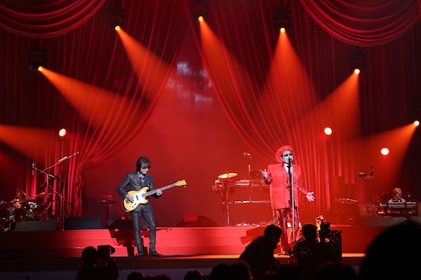 左から坂崎幸之助（Vo, G）、赤いちゃんちゃんこ姿で歌唱する桜井賢（Vo, B）。（Photo by HAJIME KAMIIISAKA）