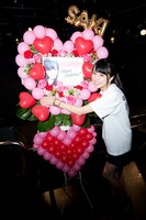 ファン有志が用意した花輪と記念撮影する四島早紀。