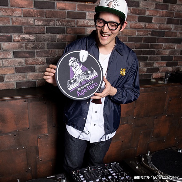 「とんかつDJアゲ太郎 スリップマット」を手にするDJ WILDPARTY。(c)イーピャオ・小山ゆうじろう / 集英社