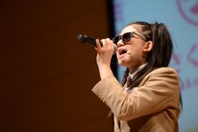 サングラスをかけてTOM☆CAT「TOUGH BOY」を歌う磯野莉音。