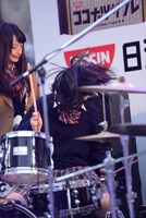 髪を振り乱しながらドラムを叩く小林歌穂。