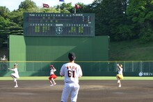 大きく振りかぶる長谷川愛里投手、其原有沙投手、田尻あやめ投手（左から）。バックスクリーンには投手6人の名前が。