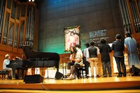 羊毛とおはな「千葉はな お別れ会」にて、千葉はな（Vo）の写真の前で楽曲を披露する羊毛こと市川和則（G）とライブのサポートメンバー、大橋トリオ、コトリンゴ。