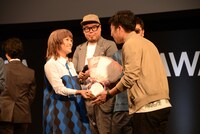 お祝いの花束を藤田晋代表取締役に手渡すIMALU。