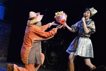 吟遊詩人（左）から突然花束を渡され素で驚く安本彩花（右）。